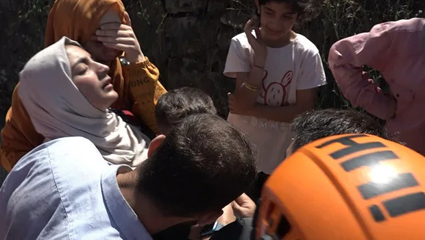 Arama kurtarma ekiplerinin çalıştığı bir alanda, sevincinden bayılan bir anne ve kurtarılan küçük bir çocuk.