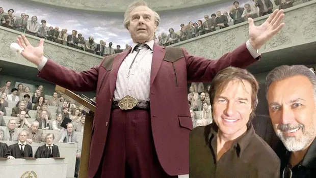 Tom Cruise'un film setinde ekiple birlikte çalışırken çekilmiş dinamik bir fotoğrafı.
