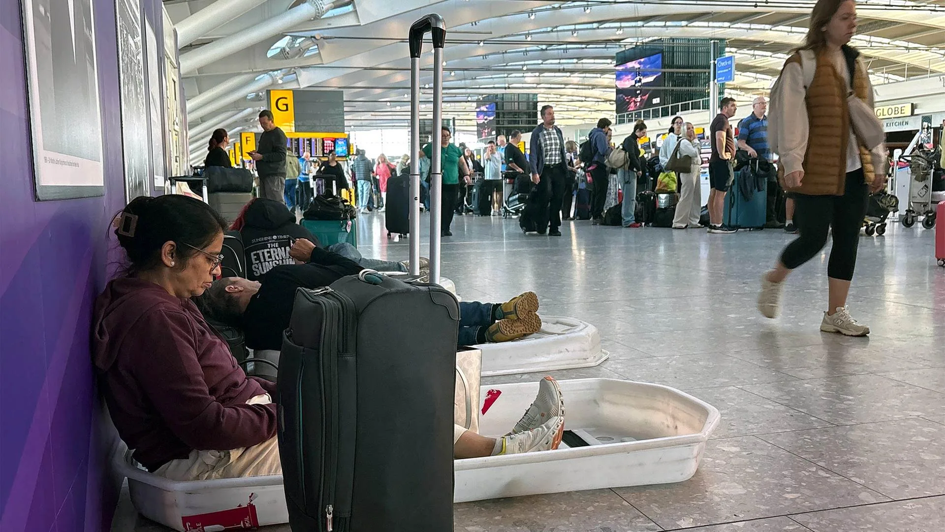 Flugpassagiere sitzen frustriert im Terminal eines Flughafens aufgrund von Flugausfällen.