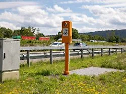 Eine orangefarbene Notrufsäule an einer deutschen Autobahn.